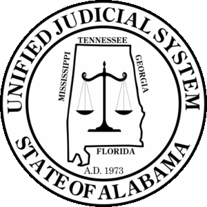 Seal of the Unified Judicial System of Alabama, featuring the state's outline with a balanced scale of justice at its center, encircled by the words 'UNIFIED JUDICIAL SYSTEM' and 'STATE OF ALABAMA'.